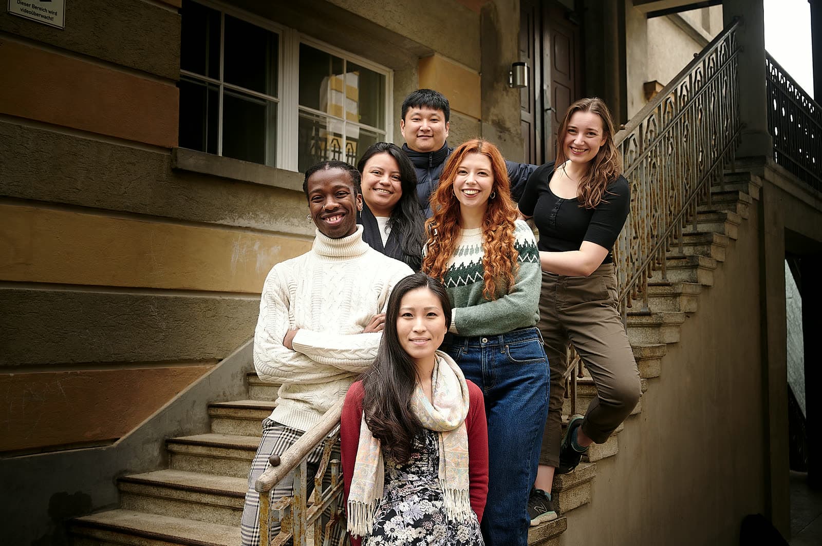 The six members of What Are We Worth? on the steps of Stella Vorarlberg